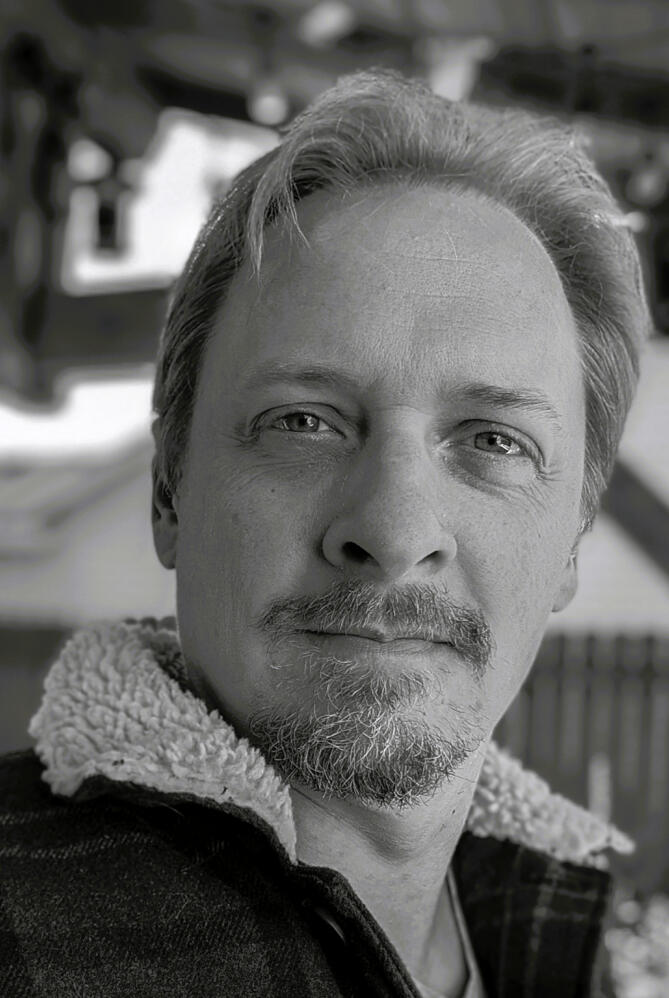 B&W photo of a man with piercing eyes, a manly beard and hair that covers the entire top of his head no problem
